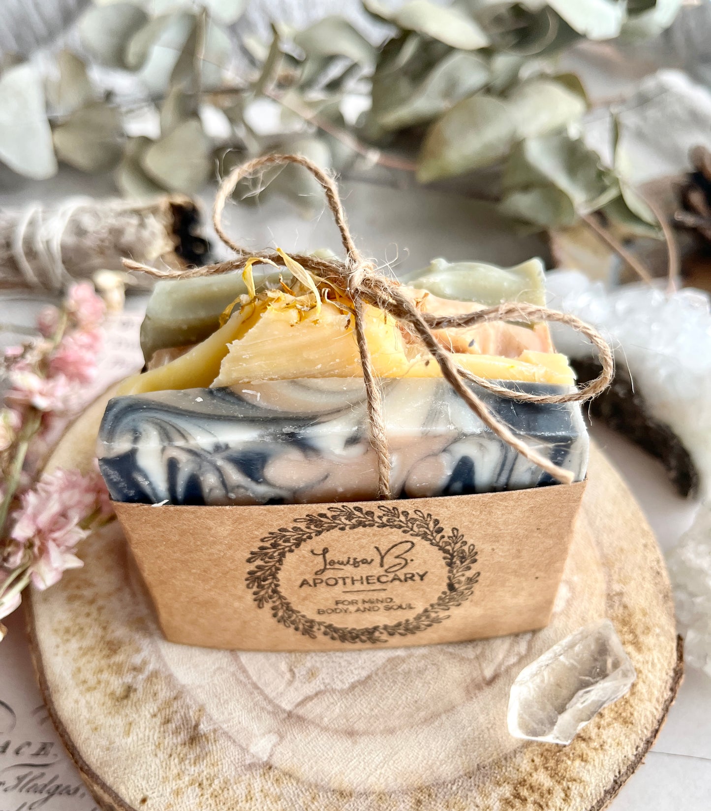 Marble-patterned soap bars with twine, on a wooden surface with eucalyptus leaves.