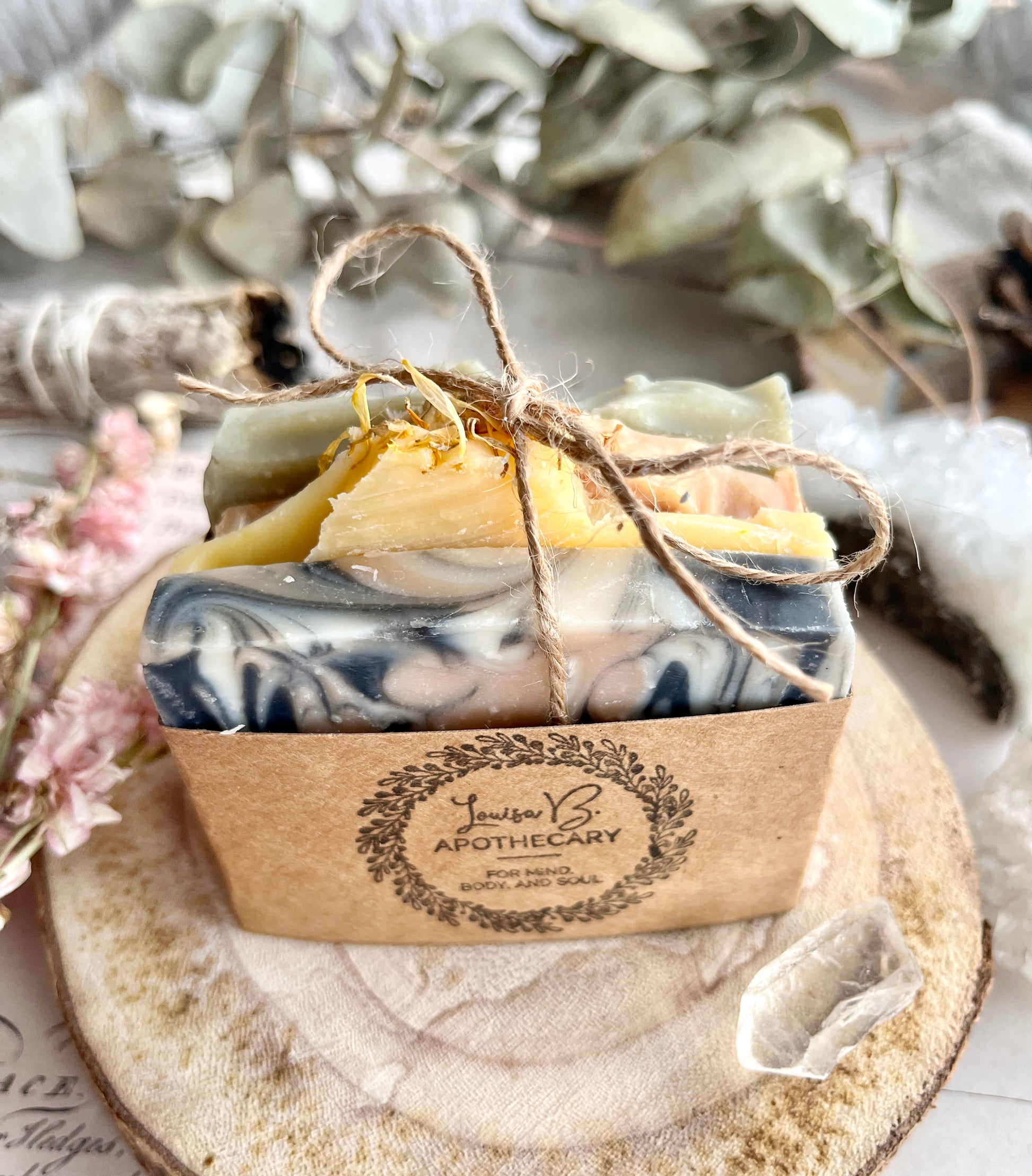 Marble-patterned soap bars with twine, on a wooden surface with eucalyptus leaves.