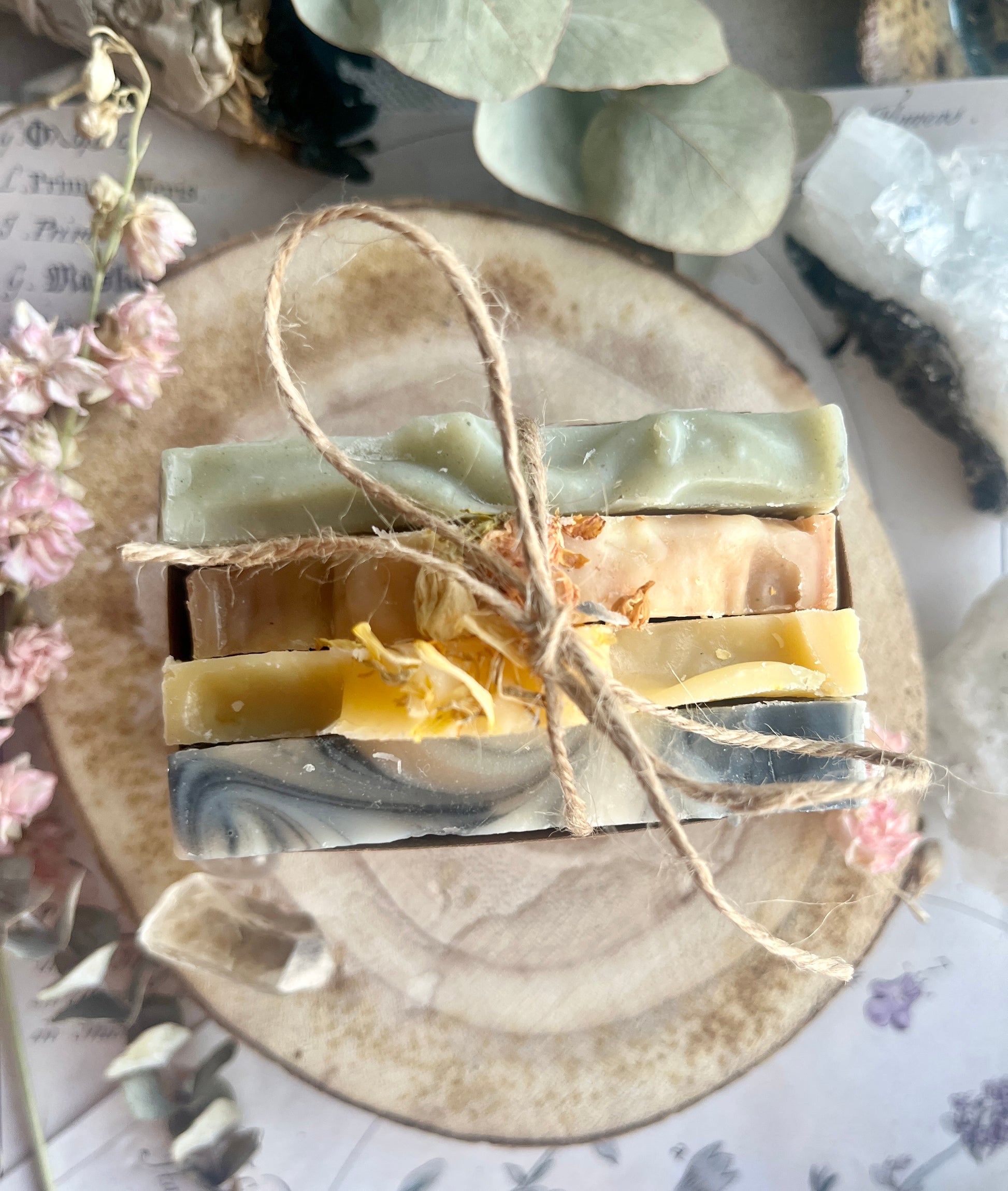 Stack of handmade soap bars tied with twine on a rustic stone surface with decorative elements.